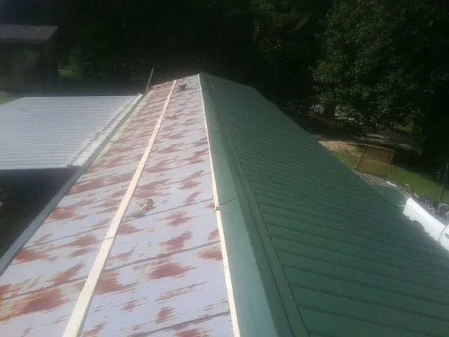 Old rusted panels beside newly installed green metal roofing — Wind Damage Roof Repair by Roofing Brothers in Lacon