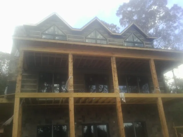 Dormers and porch framing on a large log home under construction — Roof Coating work by our crew in Lacon