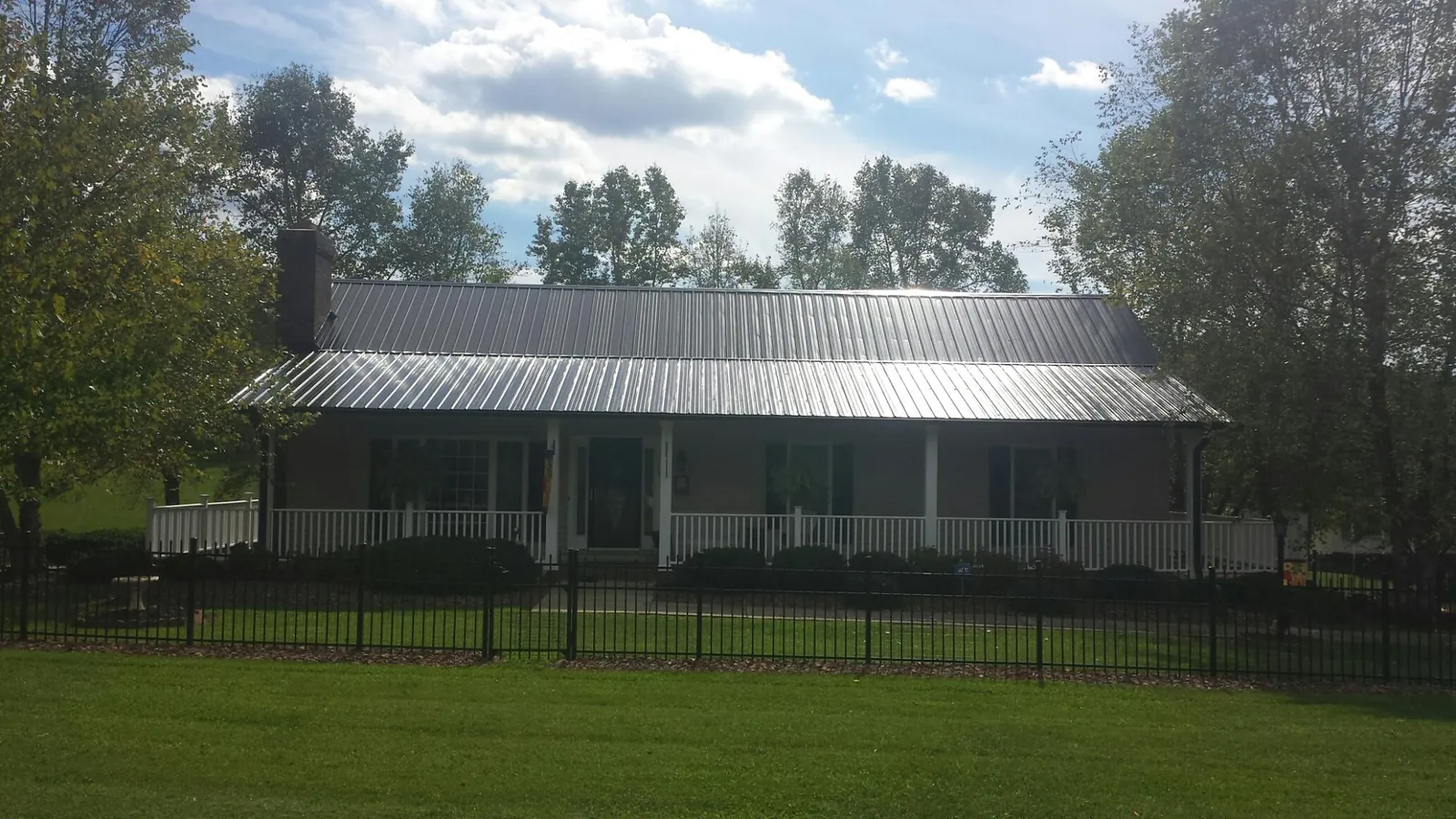 Gray metal roof on a brick ranch with a full width front porch — Gutter Guard Installation work by our crew in Lacon