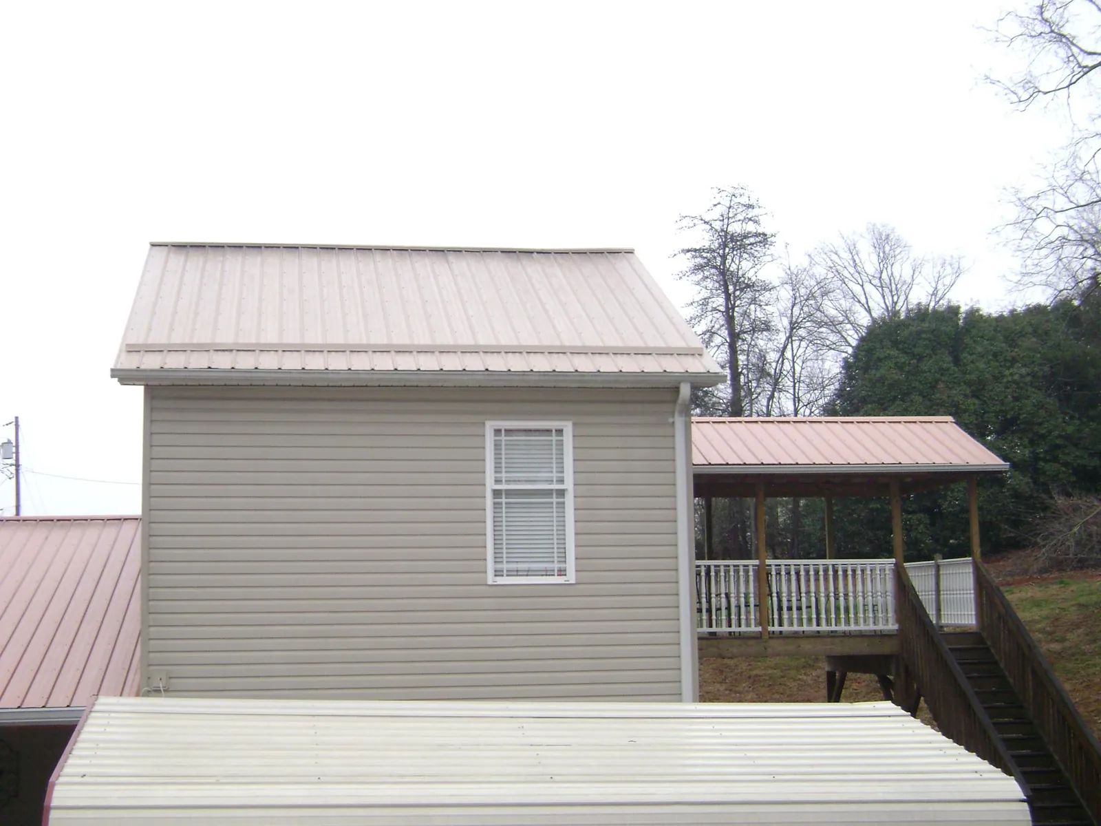 Tan metal roofs on a two story addition and attached porch, from a Roof Replacement job in Lacon